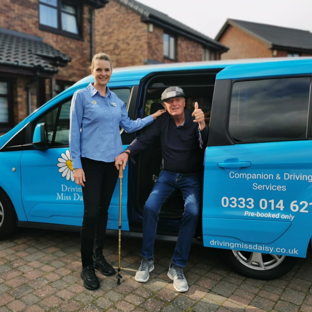 A companion driver in a driving miss daisy uniform standing next to a wheelchair accessible vehicle.