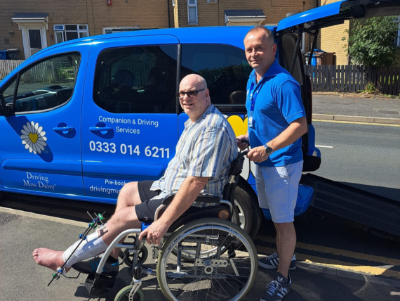 A companion driver providing patient transport to a patient in a wheelchair.