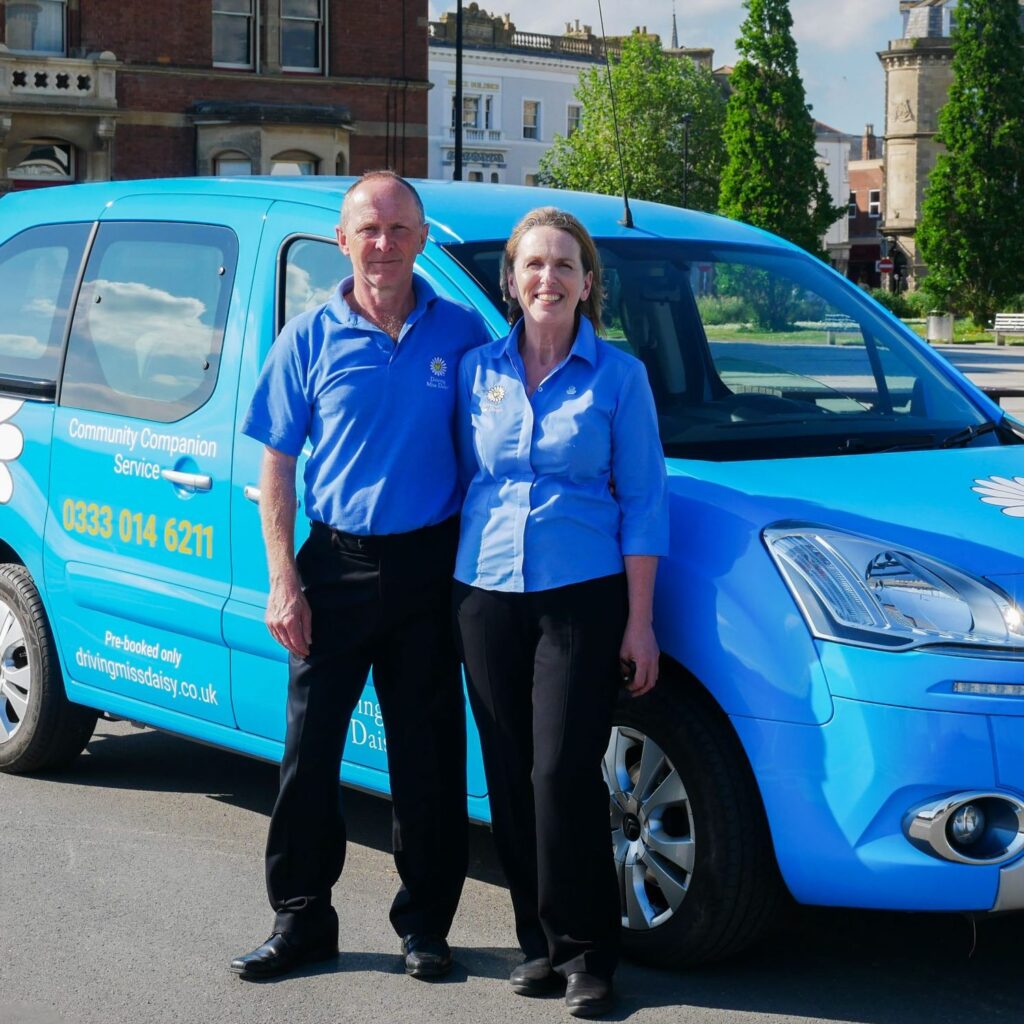 two companion drivers in driving miss daisy uniform, standing in front of a wheelchair-accessible vehicle.