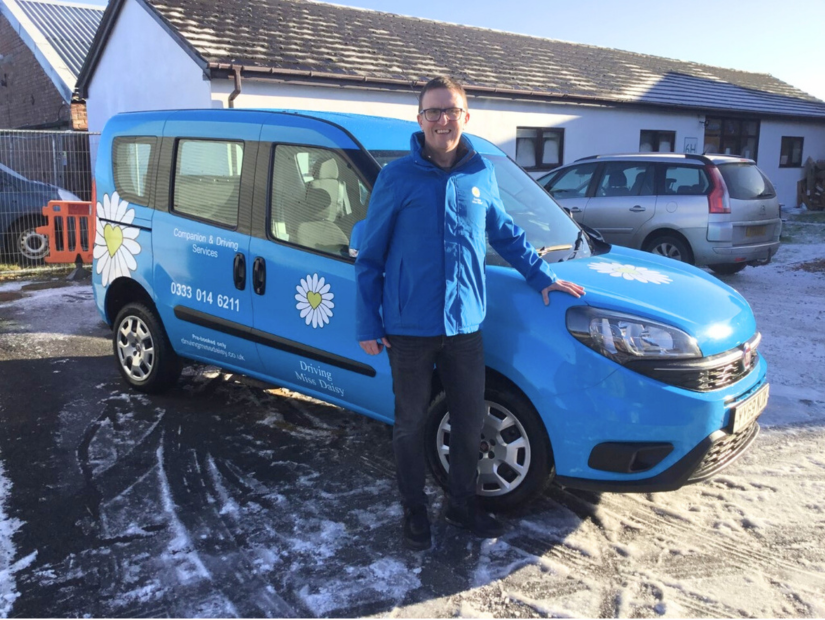 a companion driver in Driving Miss daisy uniform standing next to a wheelchair accessible vehicle.