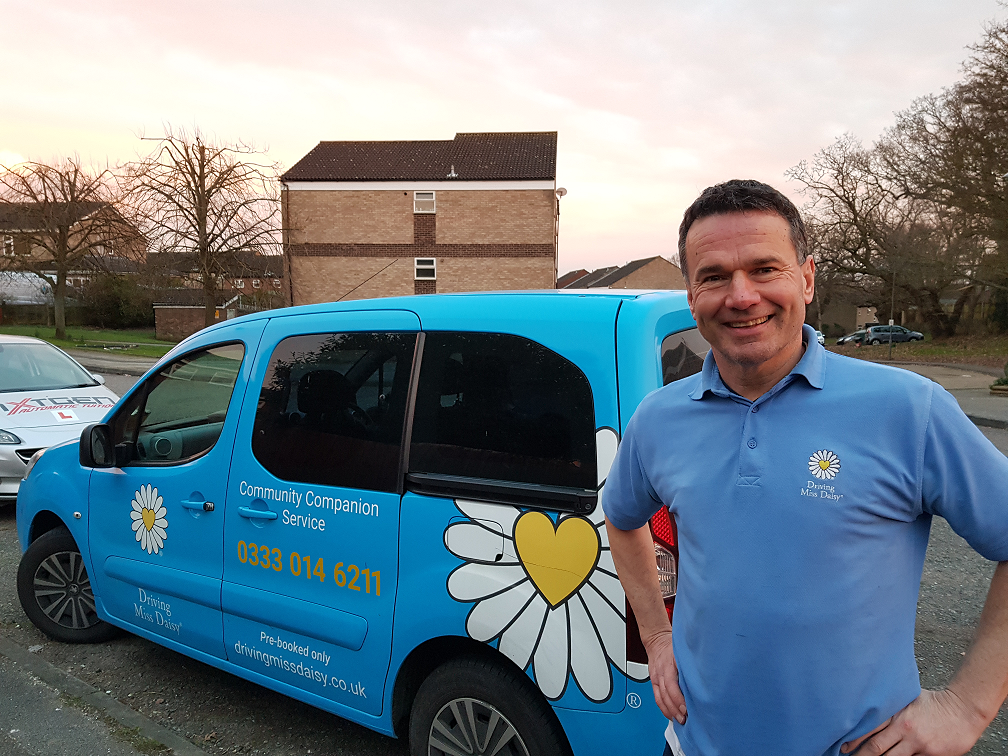 a companion driver in Driving Miss daisy uniform standing next to a wheelchair accessible vehicle.