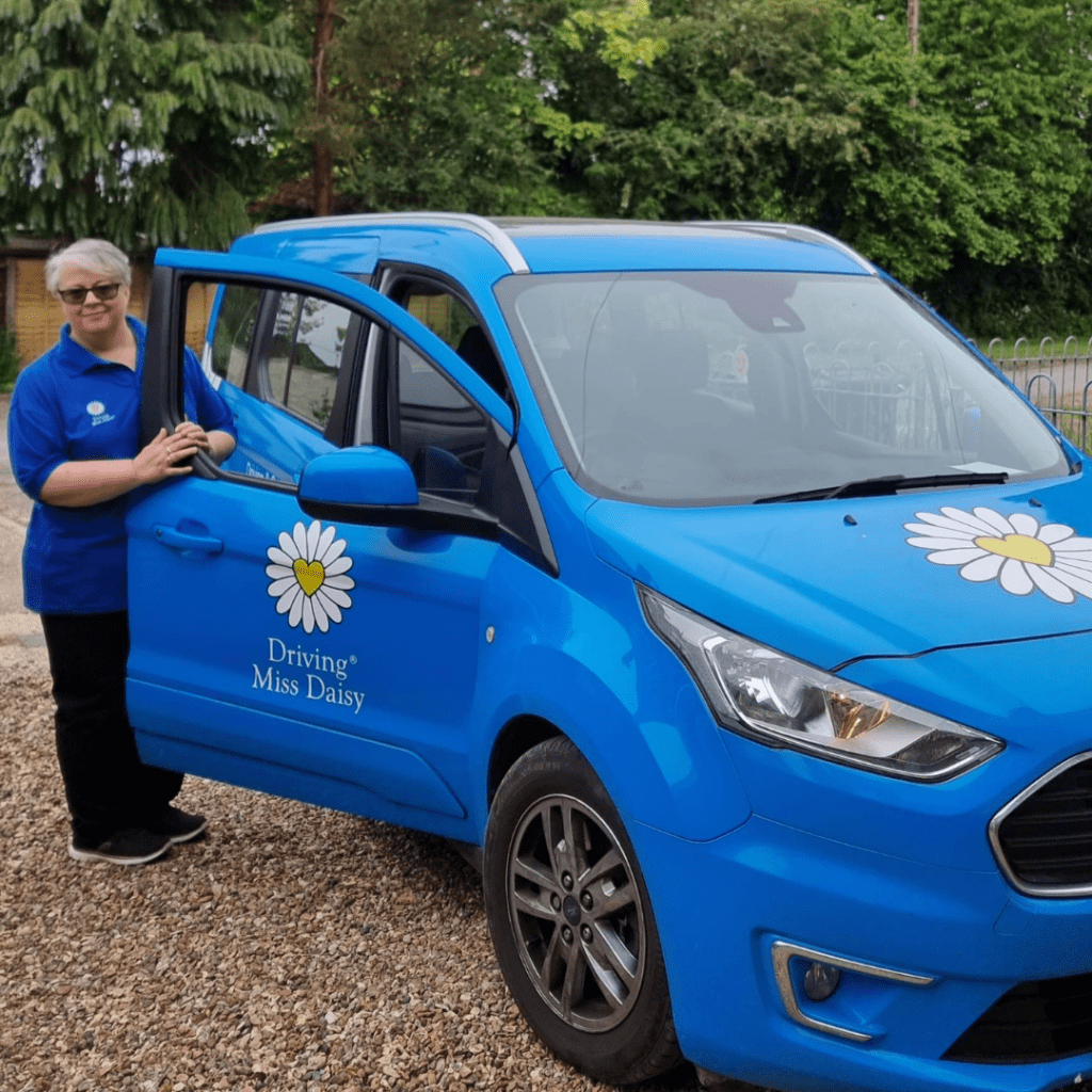 A companion driver in Driving Miss Daisy uniform, standing next to a wheelchair accessible vehicle.