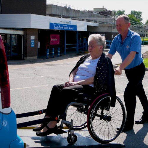 A driving miss daisy compnaion driver wheeling a patient into a wheelchair accessible vehicle